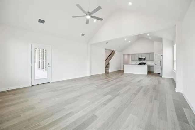 a view of empty room with wooden floor and ceiling fan