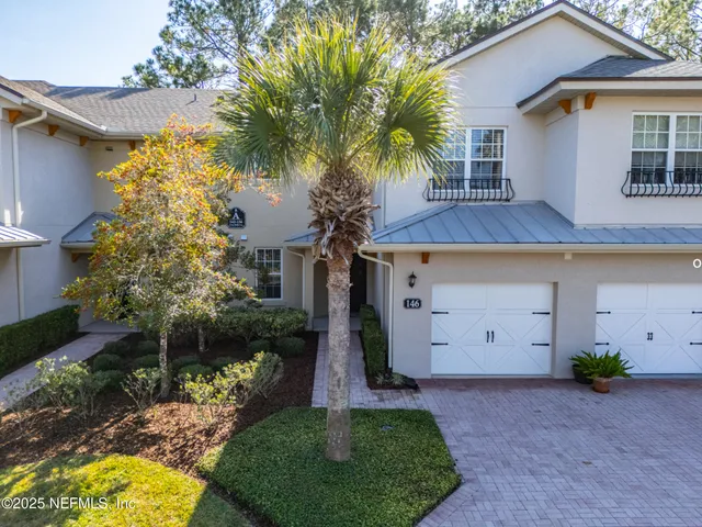 front view of house with a yard and palm trees