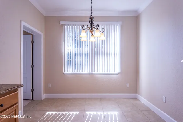 a view of an empty room with window and chandelier fan