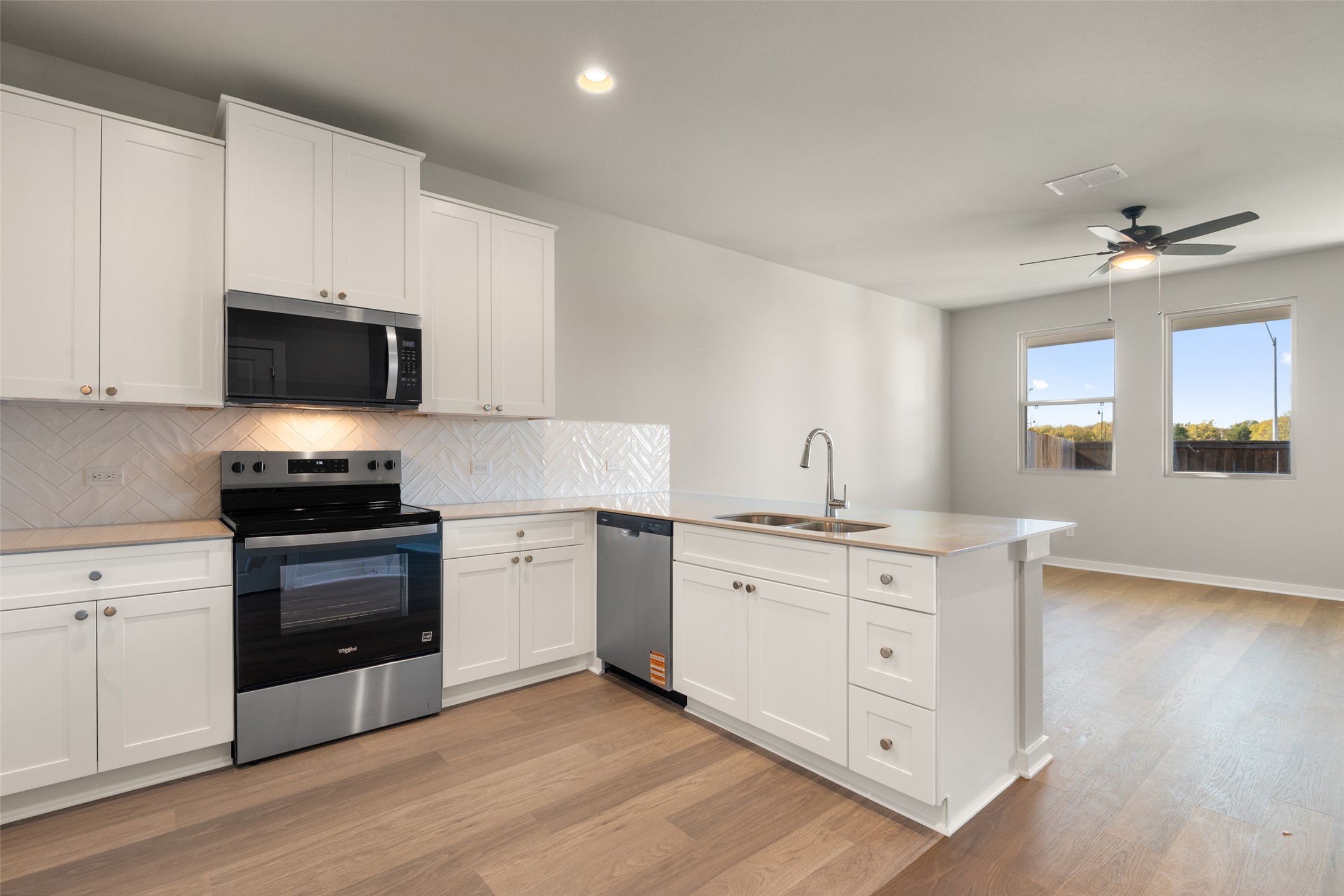 17408 Monastrell Lane Pflugerville, TX 78664 - Photo 4 of 31 Kitchen featuring appliances with stainless steel finishes, backsplash, white cabinets, a peninsula, and recessed lighting