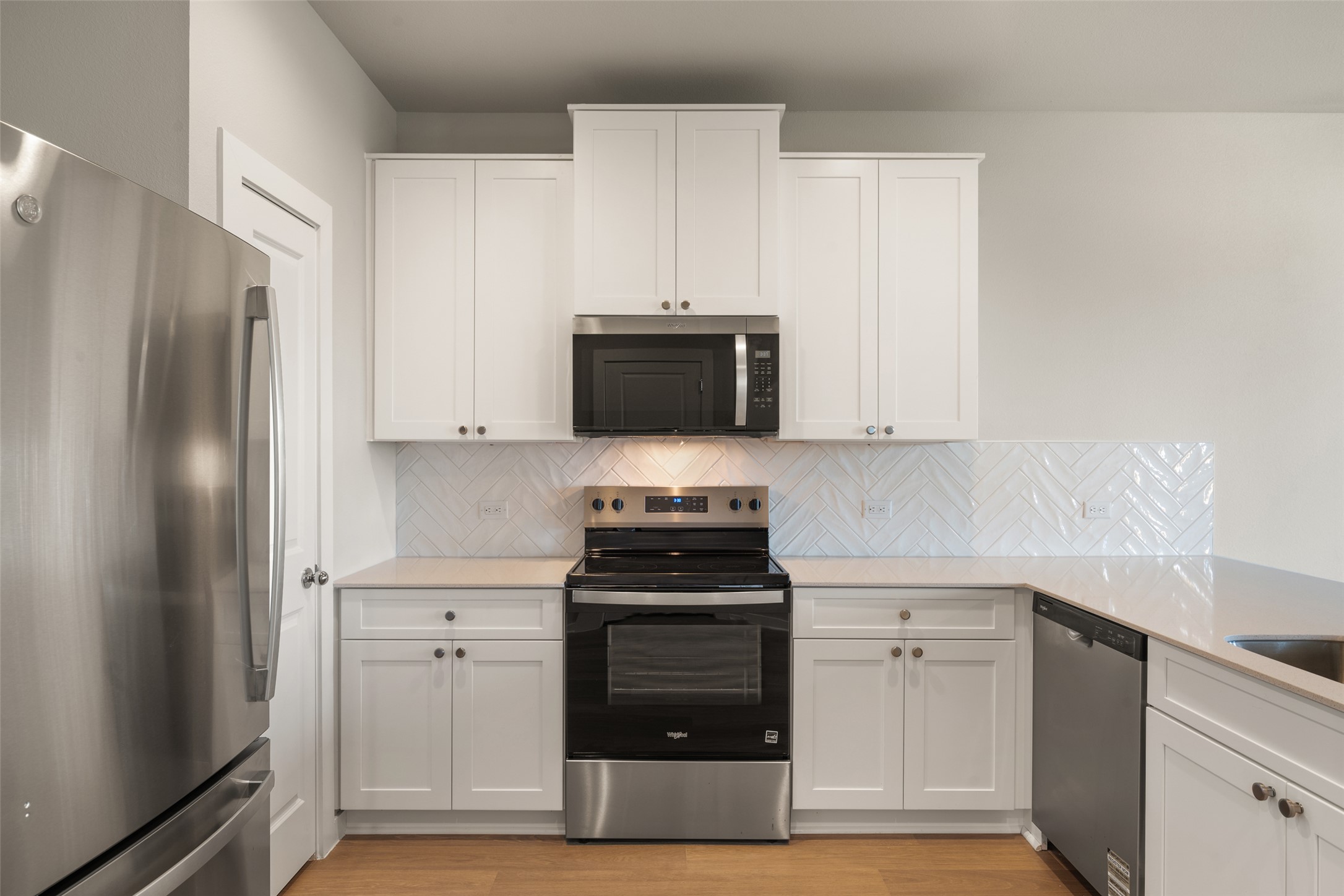17408 Monastrell Lane Pflugerville, TX 78664 - Photo 6 of 31 Kitchen featuring stainless steel appliances, white cabinets, and light stone counters