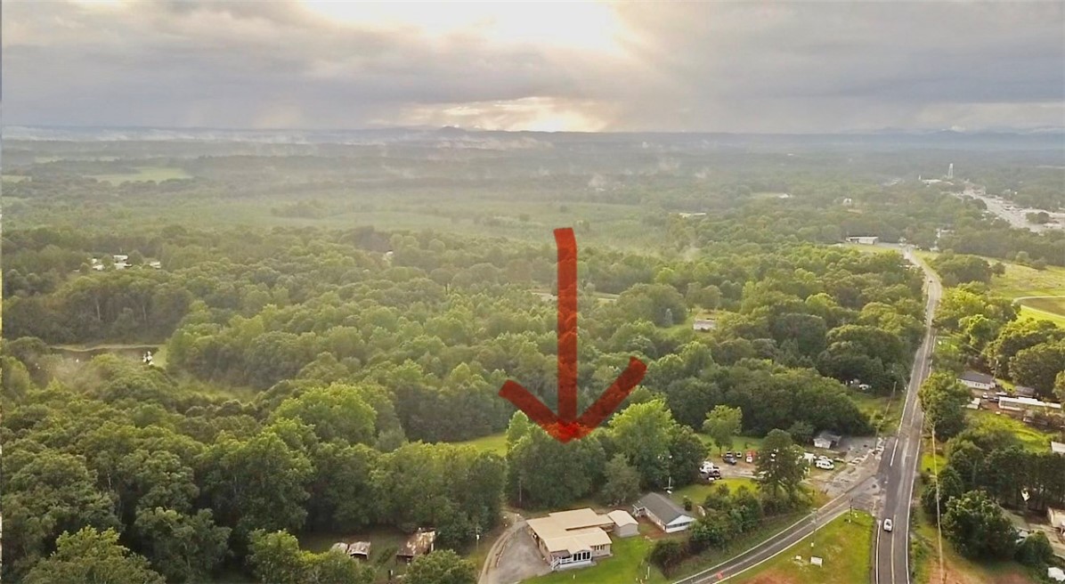 1549 Greenfield Road Westminster, SC 29693 - Photo 12 of 49 Vast, verdant landscape surrounds this property, nestled alongside a winding road under an atmospheric sky.