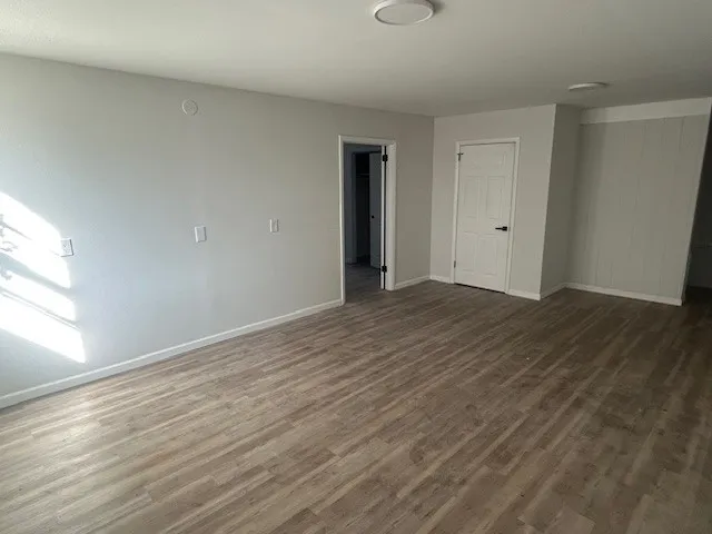 a view of an empty room with wooden floor and a window