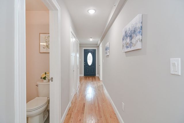 a view of a hallway with wooden floor and a bathroom