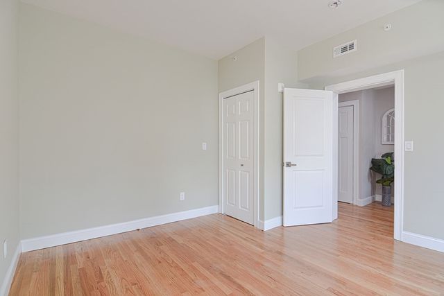 a view of an empty room with wooden floor and closet
