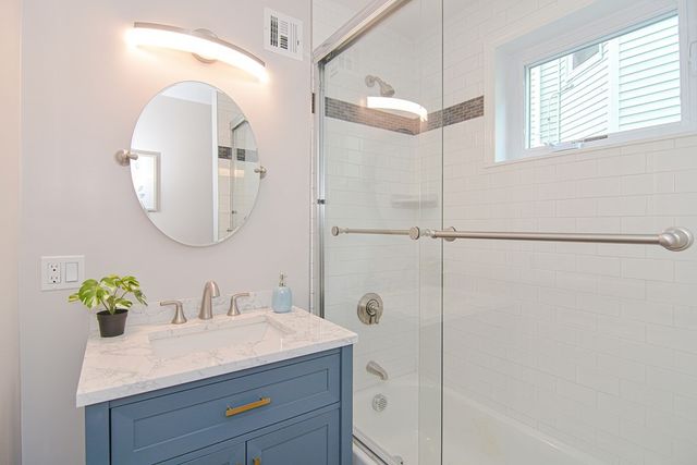 a bathroom with a granite countertop sink a mirror and a shower