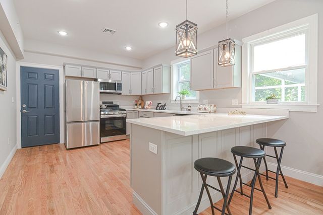 a kitchen with stainless steel appliances a table chairs refrigerator and window