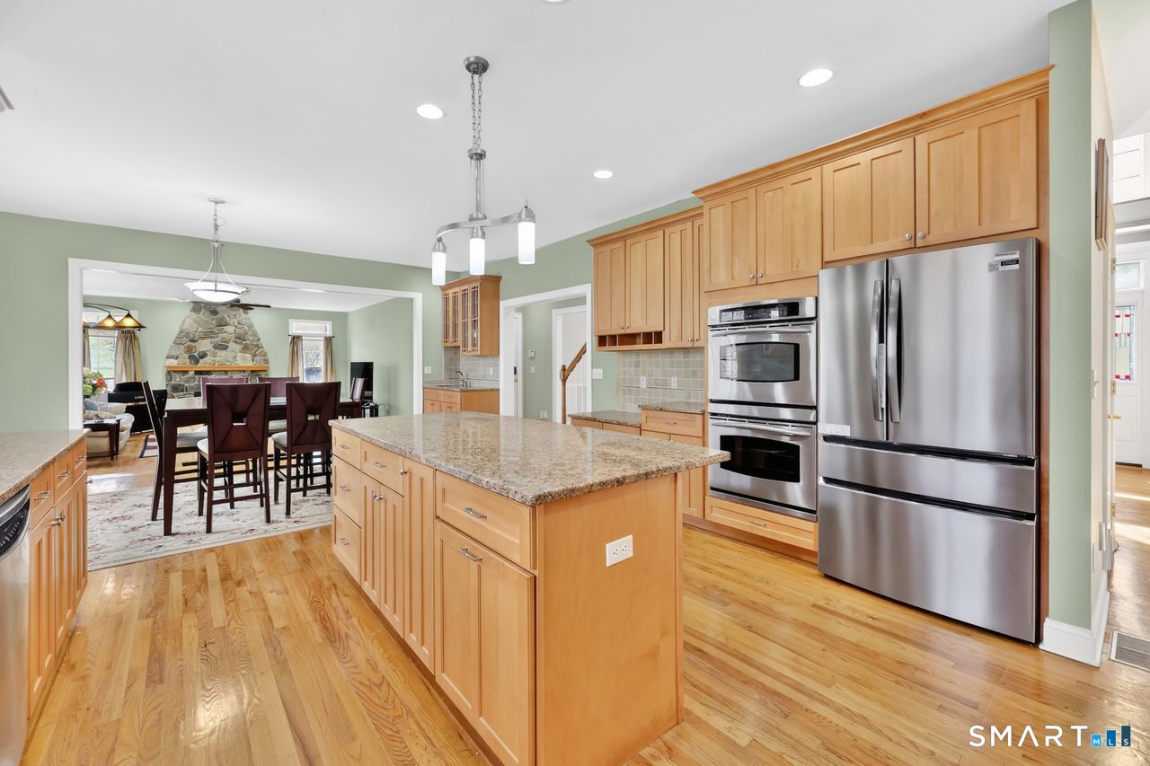 1 Bramble Trail Newtown, CT 06470 - Photo 7 of 31 a kitchen with stainless steel appliances kitchen island granite countertop a refrigerator a stove a sink and a dining table with wooden floor