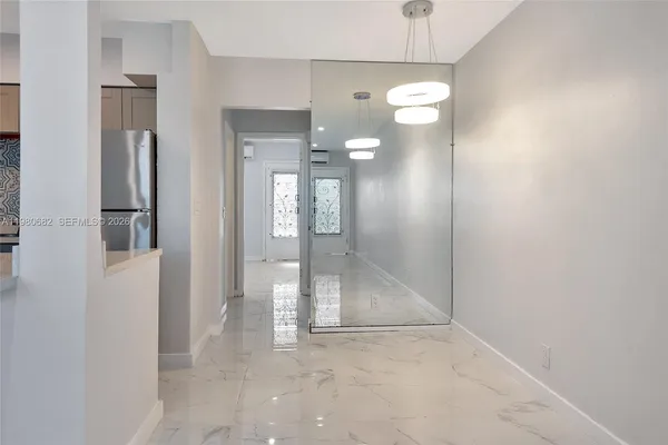 a view of a hallway with wooden floor and a chandelier