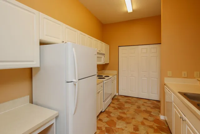 a white refrigerator freezer and a stove sitting inside of a kitchen