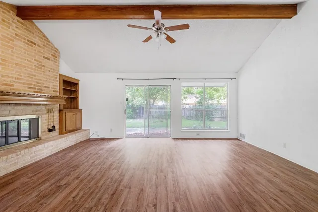 a view of an empty room with a window and wooden floor