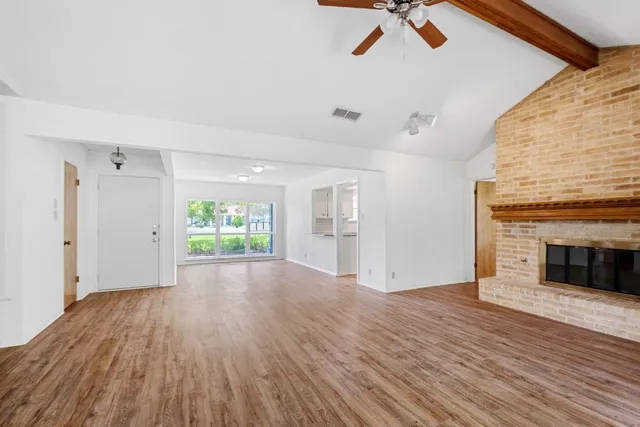 a view of empty room with wooden floor and fireplace