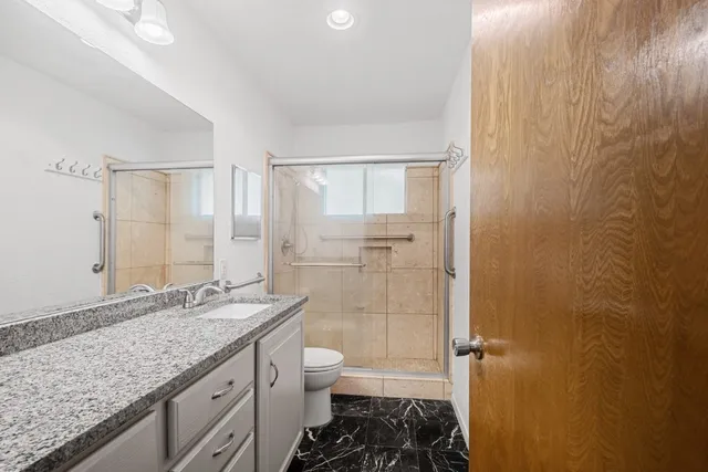 a bathroom with a granite countertop sink toilet and shower