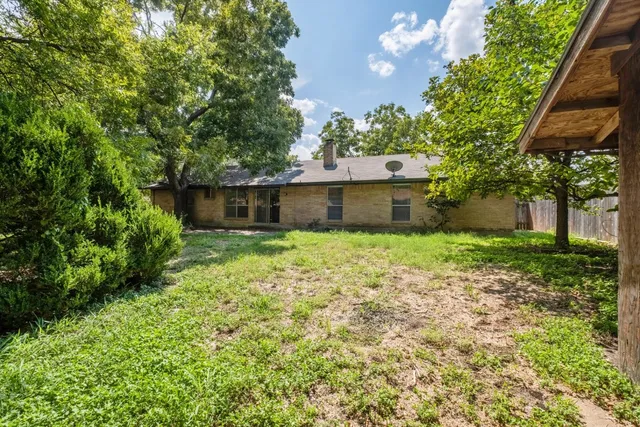 a view of a house with a yard and a large tree