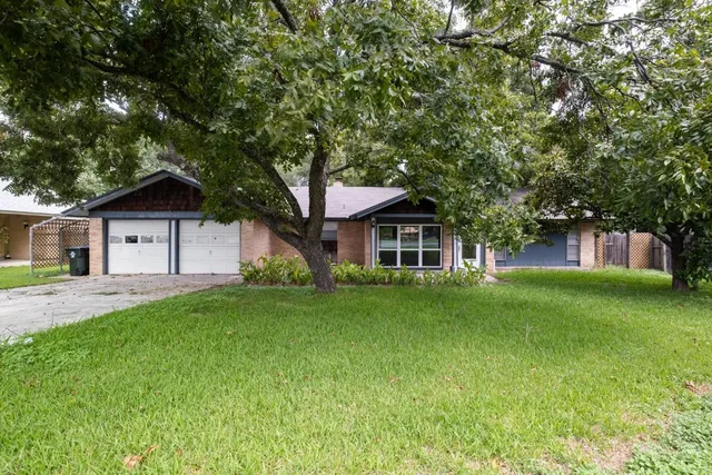 a front view of a house with a garden and trees
