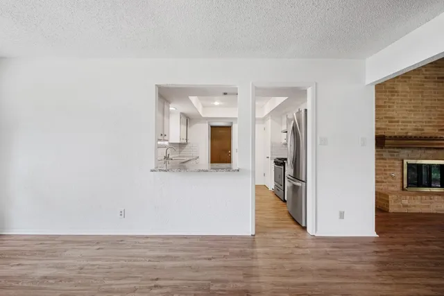 a view of an empty room with wooden floor and a fireplace