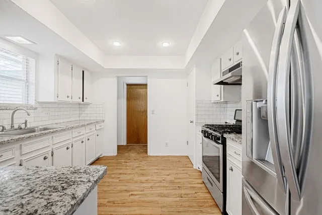 a kitchen with stainless steel appliances granite countertop a refrigerator and a sink