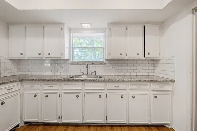 a kitchen with granite countertop white cabinets and a sink