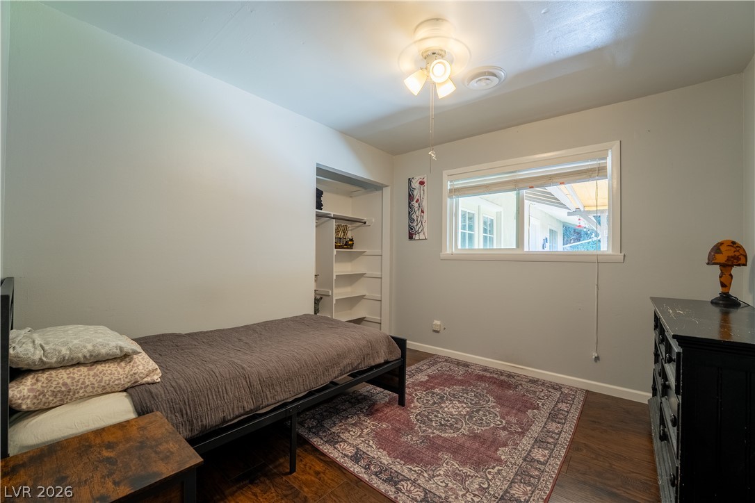 1324 Appaloosa Road Boulder City, NV 89005 - Photo 24 of 42 A cozy bedroom features wood flooring, built-in shelving, and a simple ceiling light fixture.