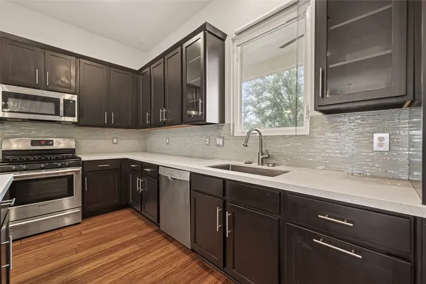 a kitchen with kitchen island granite countertop wooden floors stainless steel appliances and sink