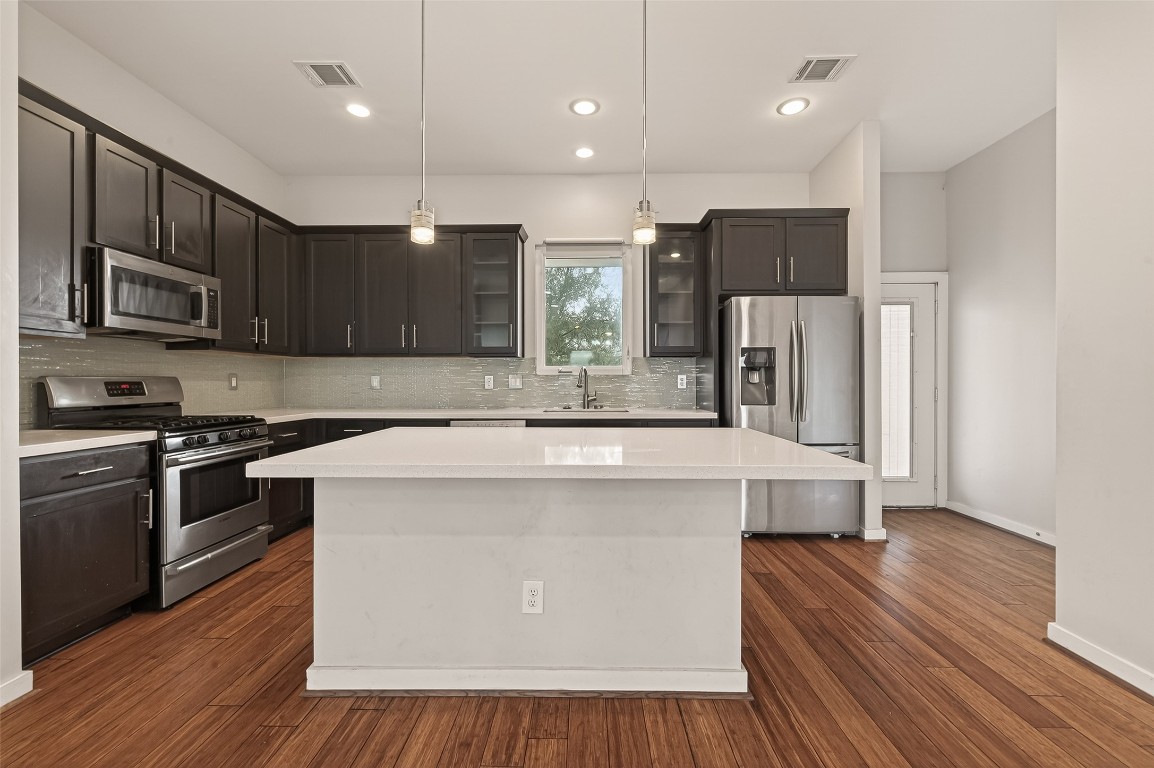 1819 South Street Houston, TX 77009 - Photo 12 of 27 a kitchen with kitchen island granite countertop wooden floors stainless steel appliances and sink