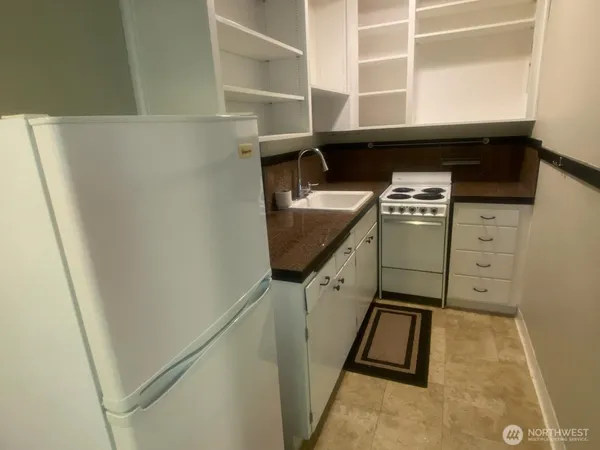 a view of a kitchen with white cabinets and a refrigerator