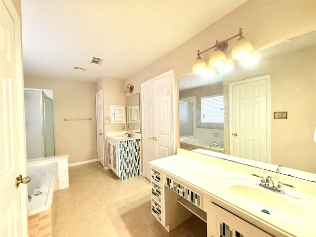 a spacious bathroom with a tub sink and mirror