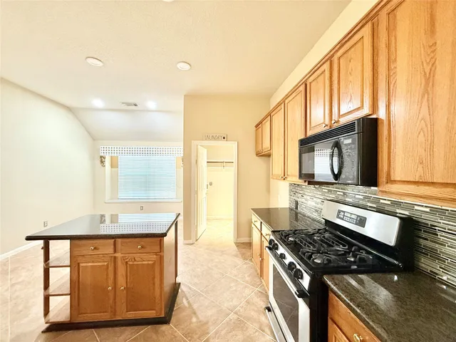 a kitchen with stainless steel appliances granite countertop a stove a sink and a microwave