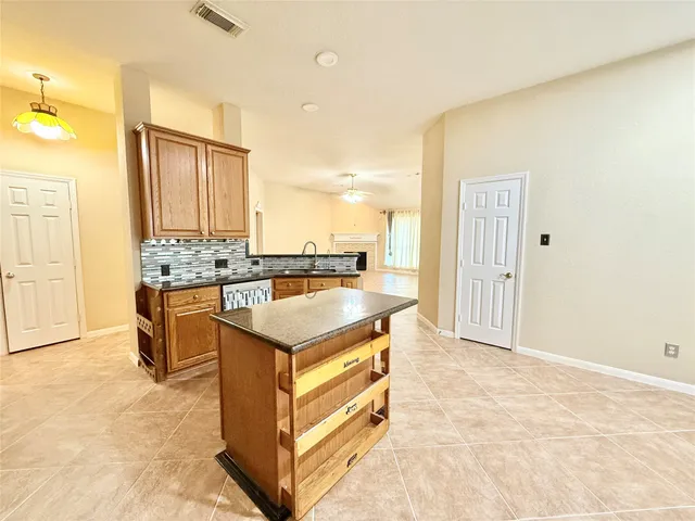 a kitchen with kitchen island granite countertop a sink stove and cabinets