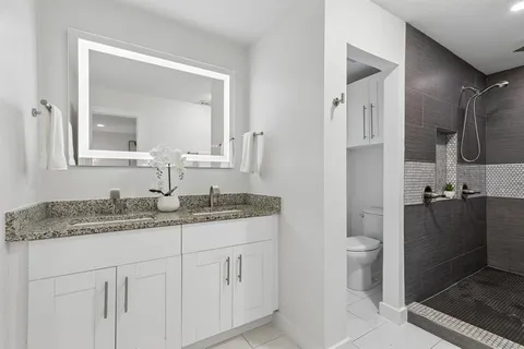 a bathroom with a granite countertop sink toilet and mirror
