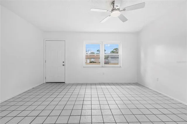 an empty room with windows and ceiling fan
