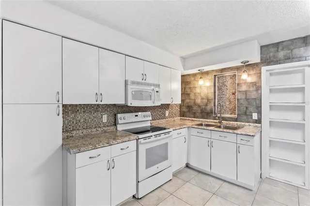 a kitchen with white cabinets appliances and a window