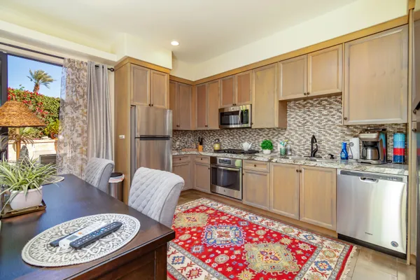 a kitchen with stainless steel appliances kitchen island granite countertop a refrigerator a stove a sink dishwasher with a dining table and chairs