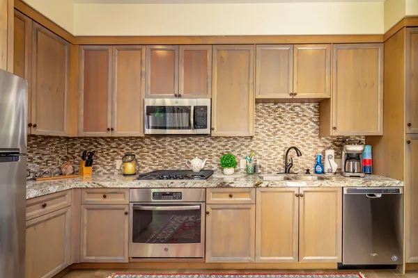 a kitchen with stainless steel appliances granite countertop a sink a stove a microwave a refrigerator and cabinets