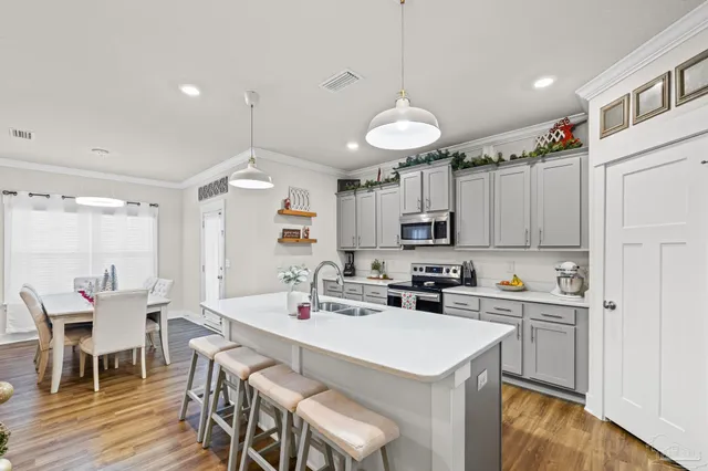 a kitchen with a dining table chairs sink and white cabinets