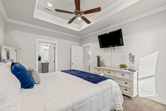 a bedroom with a bed a flat screen tv and a chandelier