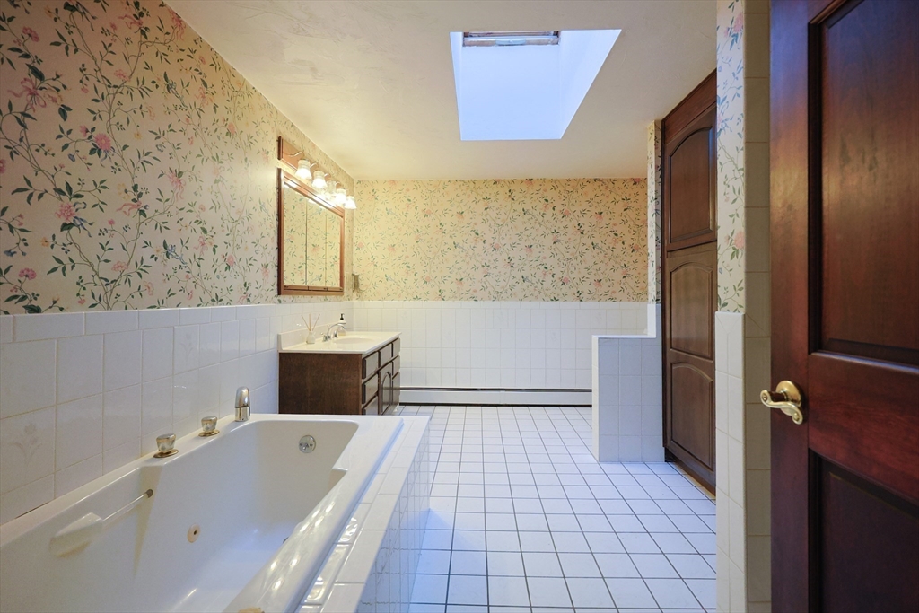 587 Common Street Walpole, MA 02081 - Photo 28 of 38 a bathroom with a tub a sink and a large mirror