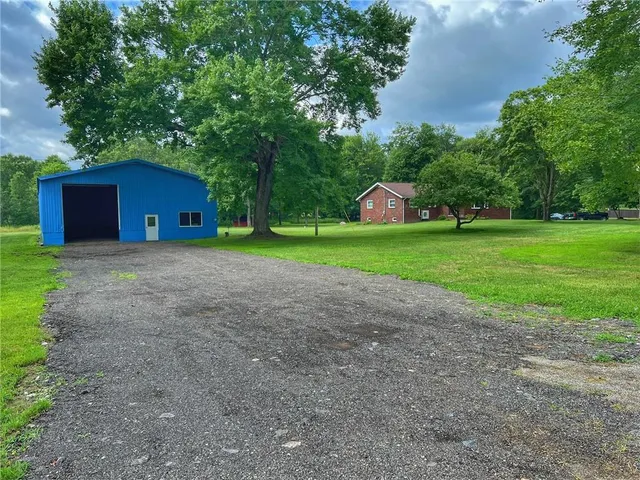 a front view of a house with a yard and tree