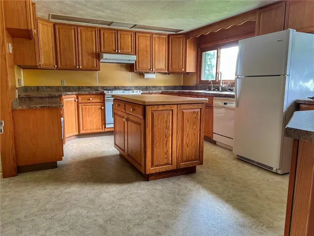 a kitchen with stainless steel appliances granite countertop a refrigerator a sink a stove and white cabinets