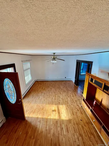 an empty room with wooden floor chandelier and windows