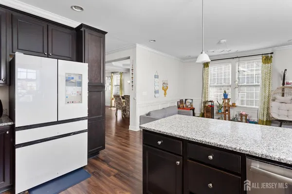 a kitchen with granite countertop a refrigerator a sink and cabinets