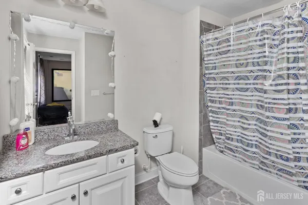 a bathroom with a granite countertop sink a toilet and shower