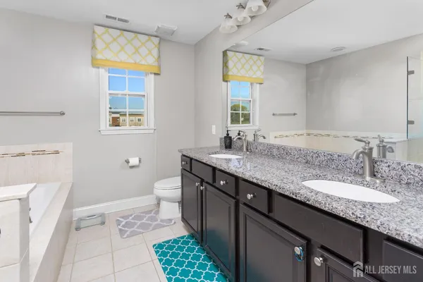 a bathroom with a granite countertop sink a toilet and a window