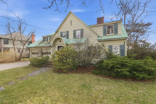 a view of a brick house with a big yard and large trees
