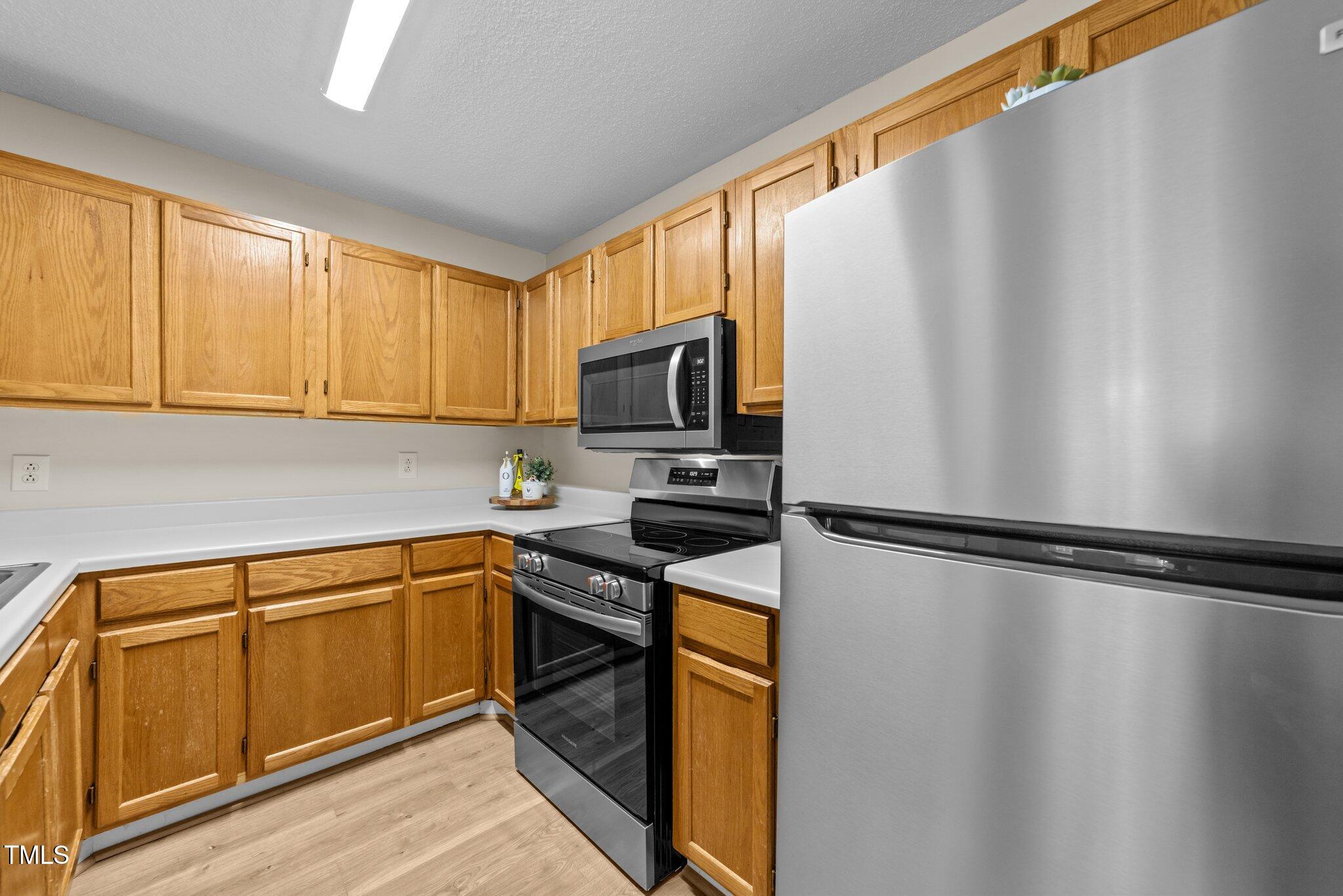4611 Timbermill Court, Unit 201 Raleigh, NC 27612 - Photo 9 of 32 a kitchen with a refrigerator a stove top oven and cabinets