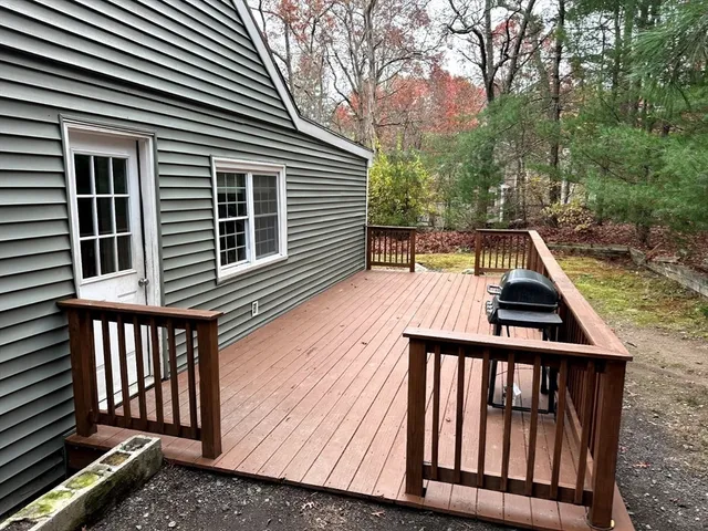 a view of house with deck and trees in the background