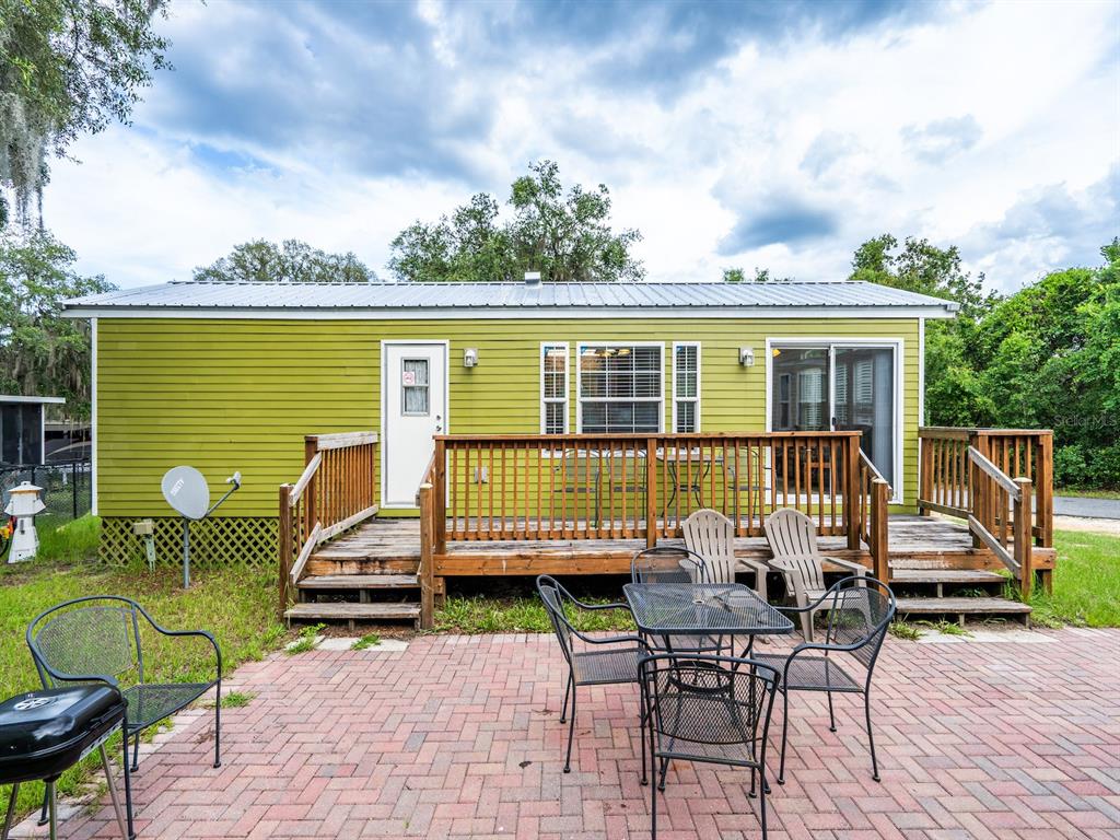 15991 Northeast 243rd Place Road, Unit 32 Fort McCoy, FL 32134 - Photo 5 of 27 a view of a patio with table and chairs with wooden floor and fence