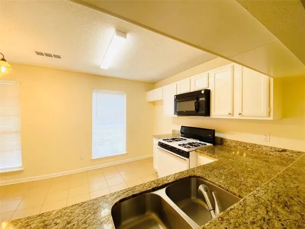 a kitchen with a sink a stove and a microwave