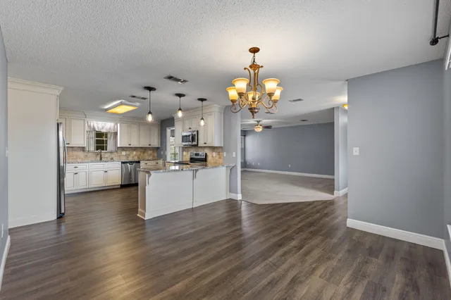 a view of a kitchen with dining table wooden floor and a refrigerator
