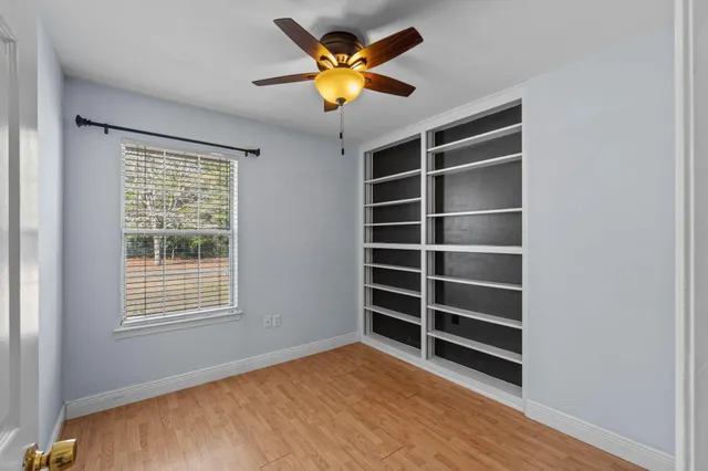 a view of an empty room with a window and a ceiling fan